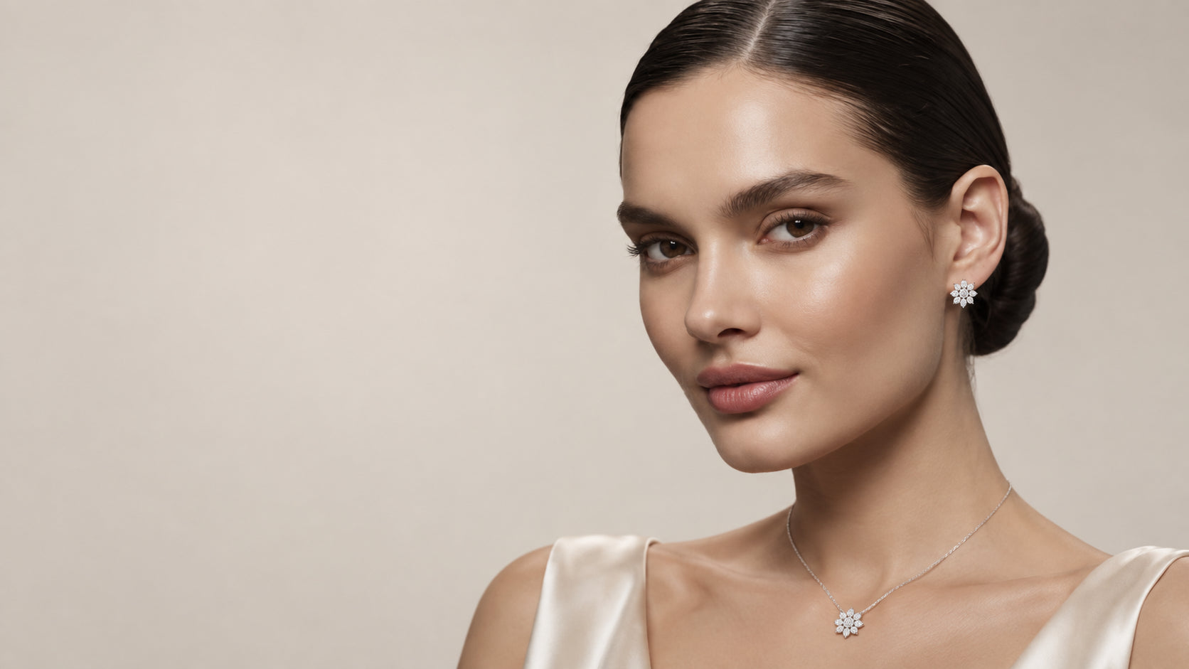 A woman wearing a flower-shaped diamond pendant necklace and matching stud earrings.